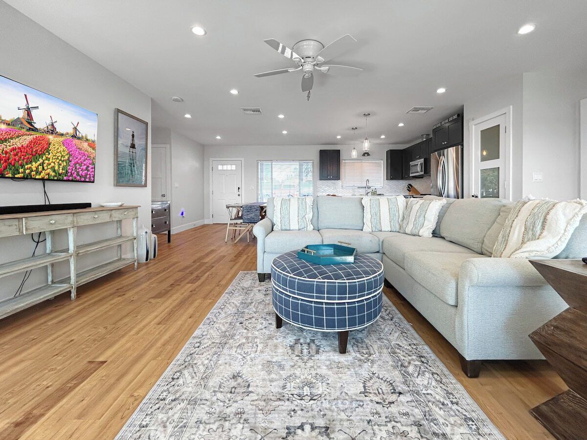 A modern living room with a sofa, ottoman, and flat-screen TV.
