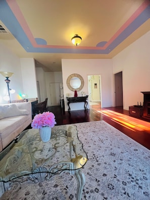 Un salon avec un canapé, une table basse ornée d’un vase de fleurs, une cheminée et un luminaire au plafond.