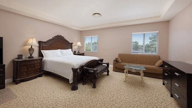 A bedroom with a large bed, a sofa, a small table, and a dresser.
