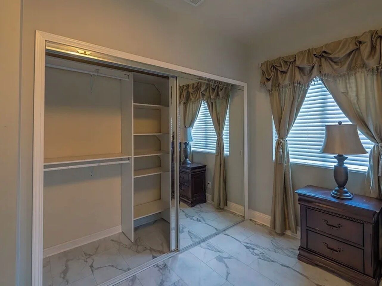 Vestidor con puertas correderas, piso de mármol y cómoda con cajones.