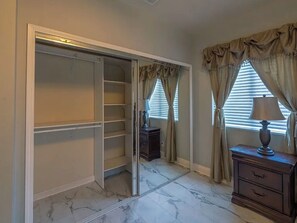 Un dressing accessible sans porte, doté de portes coulissantes, d’un sol en marbre et d’une commode à tiroirs.
