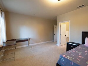 Une chambre à coucher comprenant un lit, un bureau et une porte donnant sur une autre pièce.
