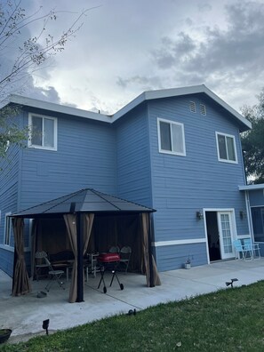 A two-story blue house with a covered patio area, a red grill, and a door leading to a garage. - Luxury 6BR Superb High End Spacious Cozy High Ceiling Arcadia Los Angeles (Monrovia)