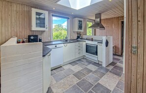 A modern kitchen with white cabinetry, a built-in oven, and a large window providing a view of the outdoors. - 3 bedroom gorgeous home in Hadsund (Hadsund)