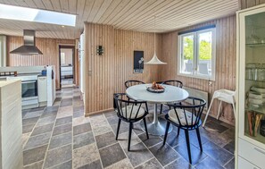A modern kitchen with a round dining table, wooden panel walls, and a large window. - 3 bedroom gorgeous home in Hadsund (Hadsund)