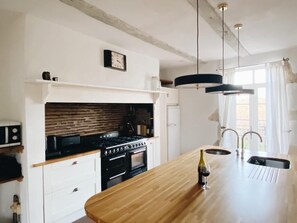 Keittiössä on puinen keittiösaareke, tiilestä tehty seinäpaneeli ja moderni liesi.