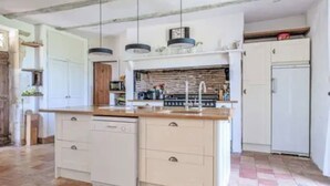 A kitchen with a central island, white cabinetry, and a tiled floor.