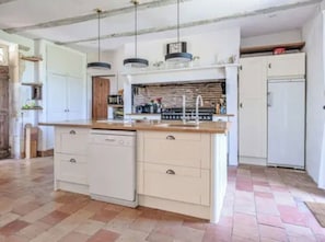 A kitchen with a central island, white cabinetry, and a tiled floor.