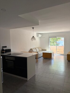 Eine moderne Küche mit einer zentralen Kochinsel, einem Essbereich mit einer Couch und einer Glastür zum Außenbereich.