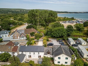A coastal residential area with houses, a parking lot, and a beach in the background. - Bayholme House - Luxury Cottages (Oxwich)