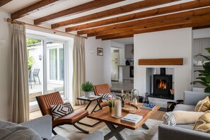 Ein modernes Wohnzimmer mit Kamin, Holzbalken und einem Essbereich.