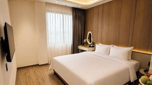 A hotel room with a large bed, a bedside table with a mirror, a flat-screen TV mounted on the wall, and a wooden floor. - DOM HOTEL DALAT (Lam Vien - Da Lat)