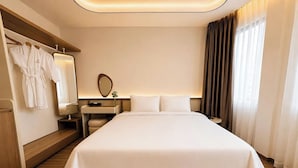 A hotel room with a large bed, a bedside table, a mirror, and a wardrobe. - DOM HOTEL DALAT (Lam Vien - Da Lat)