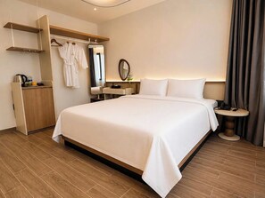 A hotel room with a large bed, bedside tables, a wardrobe, a mirror, and a small round table with a lamp. - DOM HOTEL DALAT (Lam Vien - Da Lat)