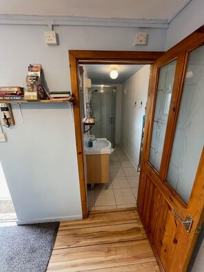 A narrow hallway leading to a bathroom with a sink and a shower. - Apartment Sleeps 3 With Parking (Swansea)