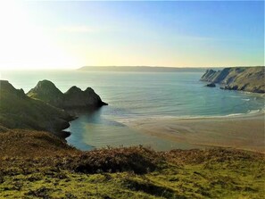A coastal landscape with a beach, cliffs, and a clear sky. - Apartment Sleeps 3 With Parking (Swansea)