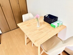A wooden table with a vase of flowers, a black basket, and a green box on it. - Raku Osaka Daikokucho Namba Shinsaibashi (Osaka)