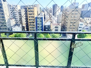 A cityscape with multiple high-rise buildings, a river, and a chain-link fence. - Raku Osaka Daikokucho Namba Shinsaibashi (Osaka)