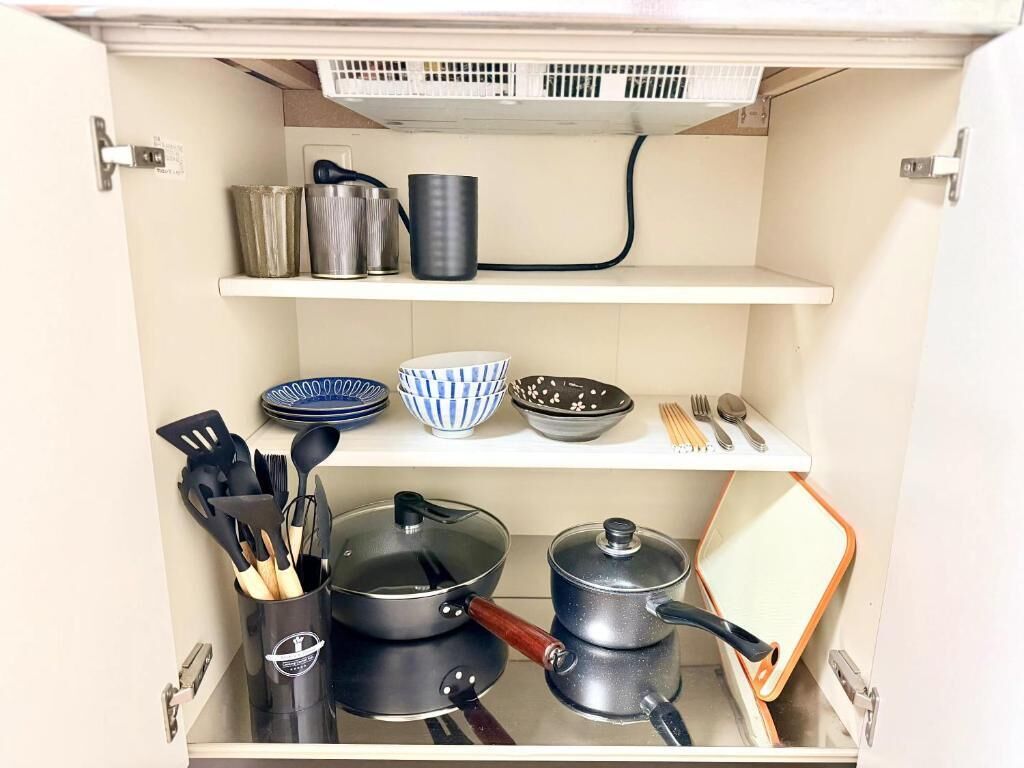 Un armario de cocina con utensilios, ollas y cuencos.