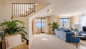 Una sala de estar moderna con un sofá, un sillón, una mesa de centro y un televisor.