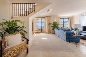 Ein modernes Wohnzimmer mit einer Couch, einem Sessel, einem Couchtisch und einem Fernseher.