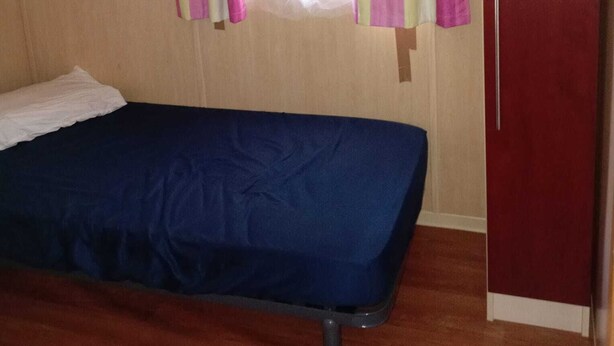 A room with a bed, a wardrobe, and curtains.