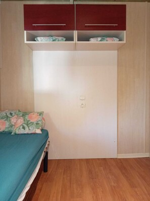 A bedroom with a bed, a wardrobe, and a nightstand.
