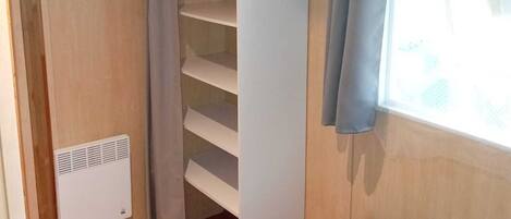Una habitación pequeña con cama, armario y ventana.