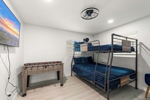Ein Schlafzimmer mit Etagenbetten, einem Deckenventilator, einem Kicker und einem Fenster mit Jalousien.