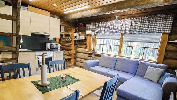 A cozy log cabin interior with a dining area, kitchen, and a sofa. - Nelostupa a by Interhome (Ylläsjärvi)