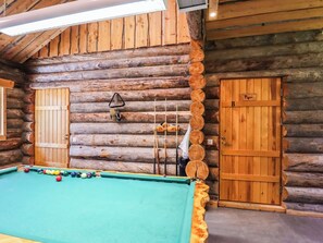 Ein Blockhaus-Interieur mit Billardtisch, zwei Türen und einer Deckenleuchte.