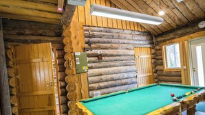 A pool table in a log cabin with wooden walls and a sloped ceiling. - Nelostupa a by Interhome (Ylläsjärvi)