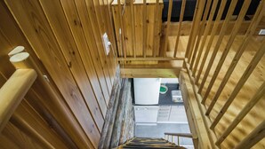 A wooden staircase leading to a room with a bed, a nightstand, and a window. - Nelostupa a by Interhome (Ylläsjärvi)