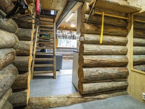 Ein rustikales Blockhaus-Interieur mit einer Holzleiter, einem Fenster mit Aussicht und einer Tür.