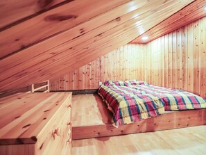 Ein Schlafzimmer im Dachgeschoss mit Holzboden, einem Bett und einer Bank.