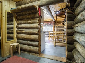 A log cabin interior with a wooden chair, a small table, and a ladder leading to a loft area. - Nelostupa c by Interhome (Ylläsjärvi)