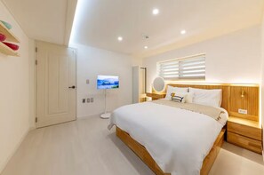 Ein modernes Schlafzimmer mit einem großen Bett, Nachttischen, einem Fernseher und einem Fenster mit Jalousien.