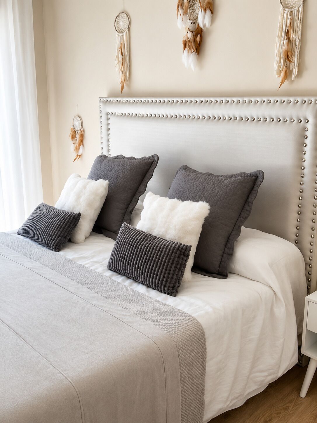 A bed with a tufted headboard, two pillows, and a white bedspread.