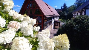 Ein traditionelles Chalet mit einem steilen roten Dach, umgeben von üppigen weißen Blumen.