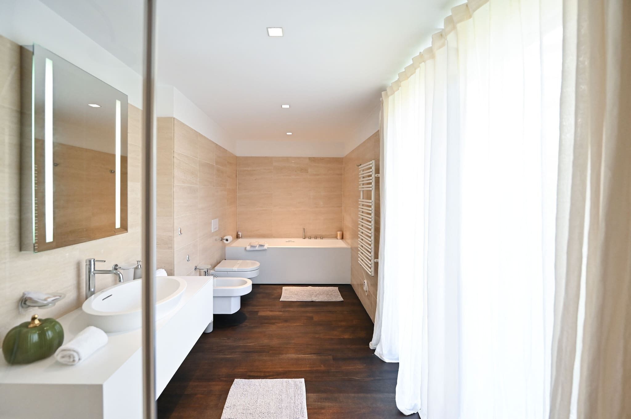 Ein modernes Badezimmer mit einer großen Badewanne, zwei Waschbecken und einem Spiegel.