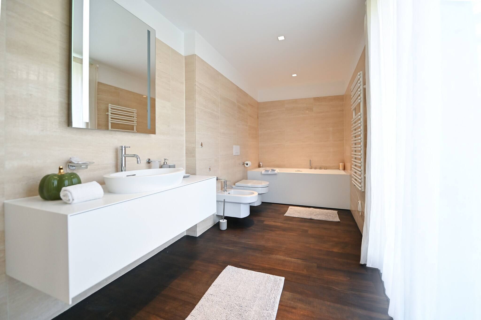 Une salle de bain moderne avec un grand miroir, deux lavabos, des toilettes et une baignoire.