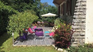 A patio area with outdoor furniture, a stone wall, and a large umbrella. - Large family home in Bagnères-de-Bigorre (Bagnères-de-Bigorre)