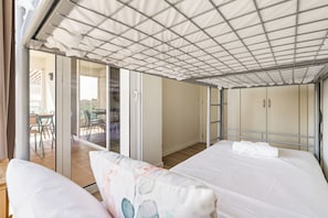 Ein Zimmer mit einem Bett, einer Couch und einer Schiebetür zu einem Außenbereich mit Tisch und Stühlen.
