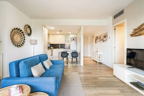 Ein modernes Wohnzimmer mit einem blauen Sofa, einem Flachbildfernseher und einem Essbereich mit Stühlen und einem Tisch.