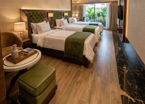 A hotel room with two beds, a sitting area with a table, and a television. - Hotel Mulki International  (Mangaluru)