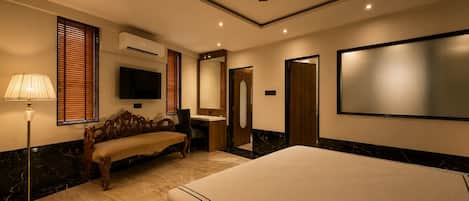 Une chambre d’hôtel équipée d’un lit, d’un bureau, d’une chaise, d’une coiffeuse avec un miroir et d’un ventilateur de plafond.