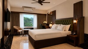 A hotel room with a large bed, a desk, a chair, a vanity with a mirror, and a window with curtains. - Hotel Mulki International  (Mangaluru)