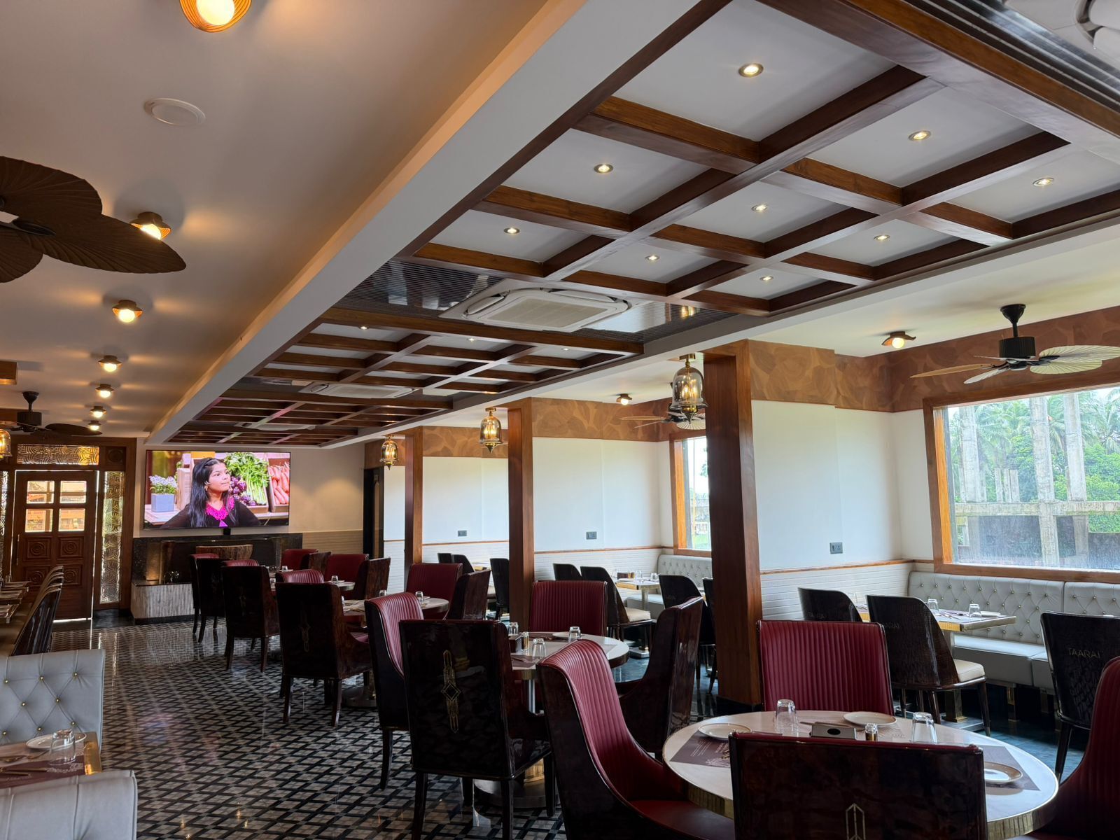 Ein Restaurant mit hoher Decke, eingelassener Beleuchtung und einem großen Fernsehbildschirm.