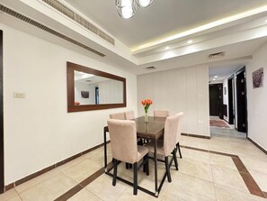 A dining area with a table and chairs, a mirror on the wall, and a hallway leading to other rooms. - Cozy 2 Bedroom apartmnet with private terrace in Swefieh (Amman)