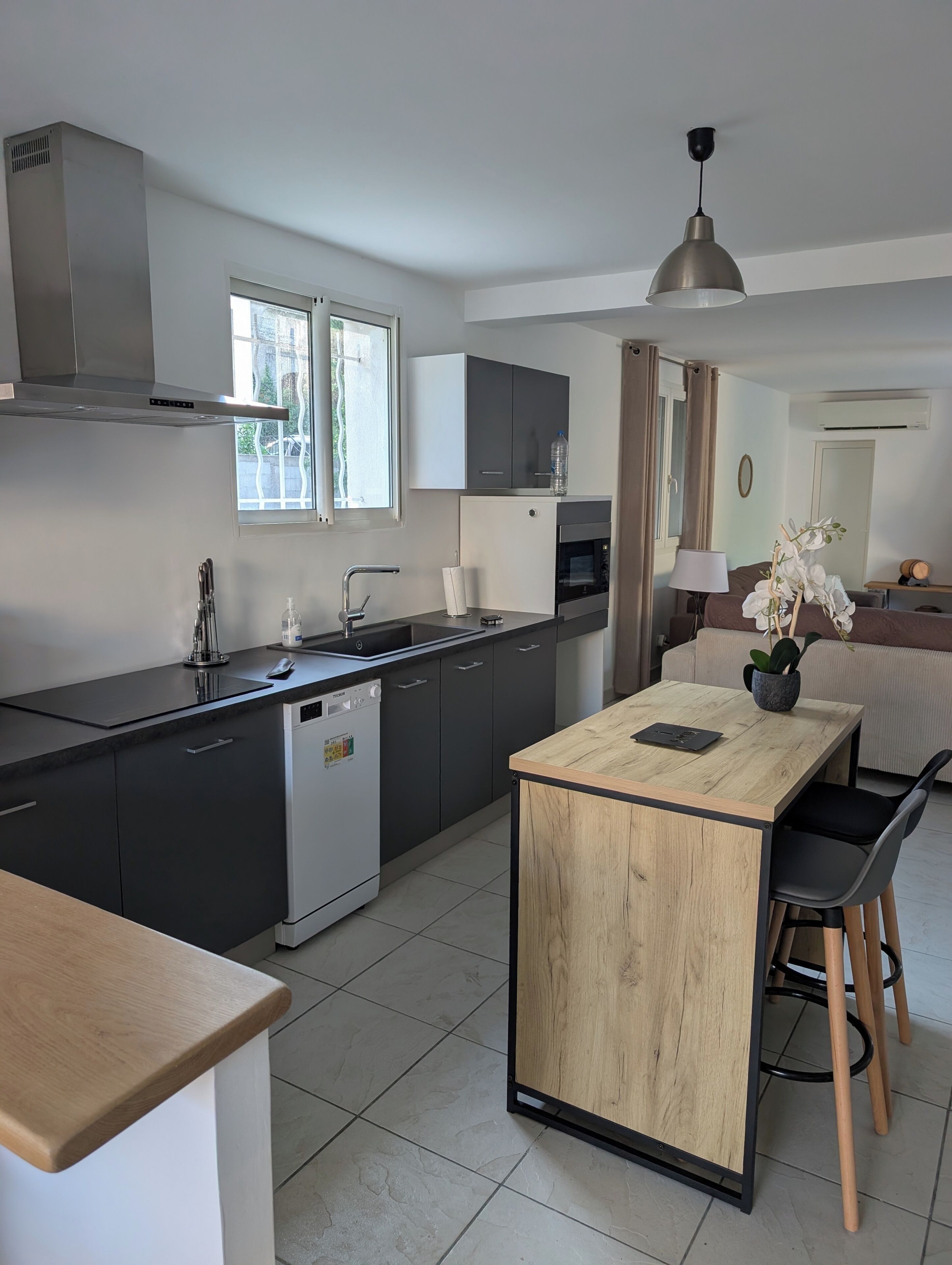 A modern kitchen with a dishwasher, oven, and a dining area with a wooden table and chairs.